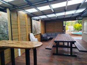a patio with two wooden tables on a deck at Location Saisonnière Les Caféiers in Le Tampon