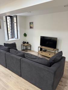 a living room with a couch and a flat screen tv at La Maison du Roi Arthur in Carcassonne