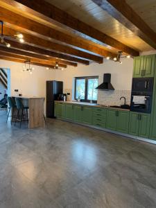 a large kitchen with green cabinets and a table at Refugiul din Deal in Mărgău