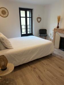 a bedroom with a large white bed and a fireplace at La Maison du Roi Arthur in Carcassonne