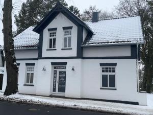 a white house with a blue roof in the snow at Ferienpark Worpswede in Worpswede