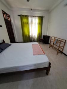 a bedroom with a bed and a window with green curtains at Home mr in Matara