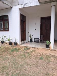 a porch of a white house with a chair and plants at Home mr in Matara