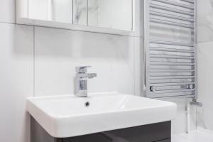 a bathroom with a white sink and a mirror at Spacious 2br Gem - Close To Clapham Junction in London +21 photos