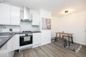 a kitchen with white cabinets and a table in it at Spacious 2br Gem - Close To Clapham Junction in London