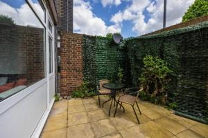 a patio with a table and chairs and a brick wall at Spacious 2br Gem - Close To Clapham Junction in London