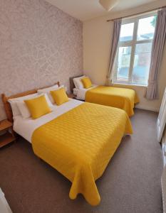 two beds in a room with yellow sheets at Sunset Suites in Blackpool