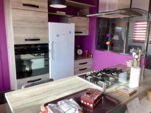 a kitchen with purple walls and a white refrigerator at Le Relais du 49 - Gîte in La Séguinière