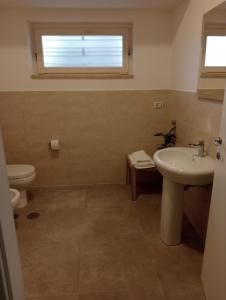 ein Badezimmer mit Waschbecken, Toilette und Fenster in der Unterkunft Dimora Cristella in Eboli + 11 Fotos