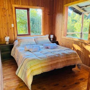 a bed in a wooden room with two pillows on it at Cabaña 2 - Rancho Doble AA in La Junta