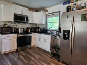 a kitchen with white cabinets and a stainless steel refrigerator at Villa Nemesio & Linsday 1 in Atlanta