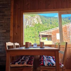 a wooden table with chairs and a large window at Cabaña 2 - Rancho Doble AA in La Junta