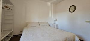 a white bedroom with a bed and a clock on the wall at Al Castello di Valdengo in Valdengo