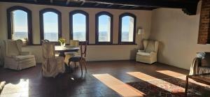 a living room with a table and chairs and windows at Al Castello di Valdengo in Valdengo