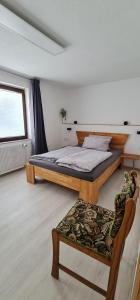 a bedroom with two beds and a chair and a window at Pension am Bach Nice Dreamis in Fuldatal