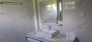 a white bathroom with a sink and a mirror at Bhagya Resort Limited in Nikawatawana
