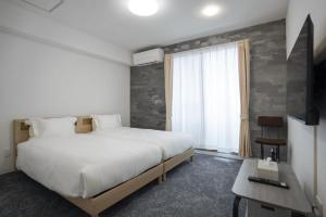 a bedroom with a large white bed and a window at Laon Inn Plus Miyakojima in Miyako-jima