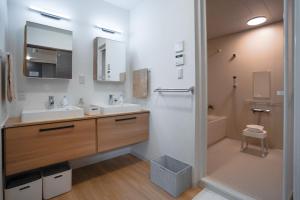 a bathroom with a sink and a toilet and a mirror at Laon Inn Plus Miyakojima in Miyako-jima