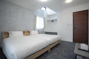 a bedroom with a large white bed and a window at Laon Inn Plus Miyakojima in Miyako-jima