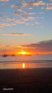 a sunset on the beach with boats in the water at Sunset House Herradura in Herradura