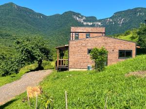 a house on a hill with mountains in the background at Refúgio com Vista para os Canyons e Hidromassagem in Praia Grande