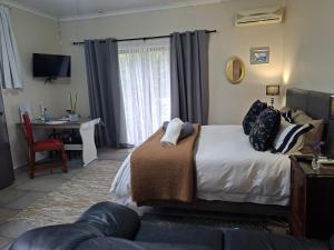 a bedroom with a bed and a table and a desk at 1-On-Scott Garden Suites in Somerset East