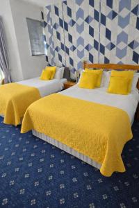 two beds in a hotel room with yellow sheets at Sunset Suites in Blackpool