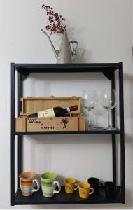 a shelf with a bottle of wine and cups and wine glasses at Palma's house in Cambiago +22 photos