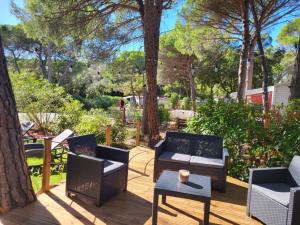 a patio with chairs and a table and trees at Mobil-home Oasis Village Club in Puget-sur-Argens