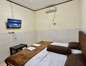 two beds in a room with a tv on the wall at Cailendra in Yogyakarta