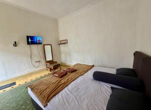 a bedroom with a bed and a tv on the wall at Cailendra in Yogyakarta