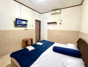 a bedroom with a bed with a tv on the wall at Cailendra in Yogyakarta