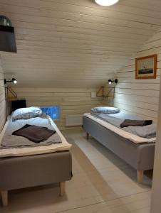 two twin beds in a room with wooden walls at Navy Condo for 6, free parking in Turku