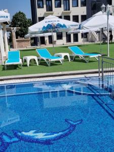a swimming pool with two blue chairs and umbrellas at Hotel Global Palace in Haskovo