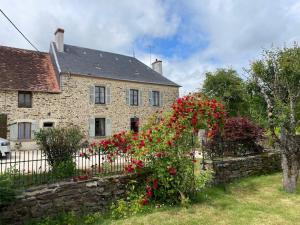 a stone house with a fence and red flowers at Georgie et Margot - Chambres d'hotes et Gite in La Châtre-Langlin