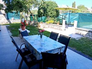 a table with chairs and a table with flowers on it at Apartment Glavani with Pool in Barban