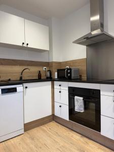 a kitchen with white cabinets and a black oven at L'écrin orange, Wifi et parking gratuit in Chalons en Champagne +13 photos
