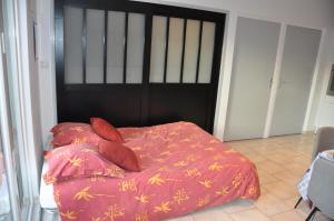 a bed with a red comforter and two pillows at La cadole de Clem in Juliénas +4 photos