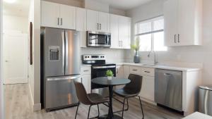 a kitchen with a stainless steel refrigerator and a table at Landing Apartments - 2720 S Federal in Englewood