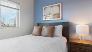 a bedroom with a white bed with a lamp and a window at Landing Apartments - 2720 S Federal in Englewood