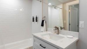 a white bathroom with a sink and a tub at Landing Apartments - 2720 S Federal in Englewood +11 photos