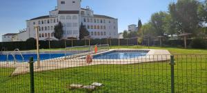 a fence in front of a swimming pool with a building at Apartamento acogedor El portil in El Portil
