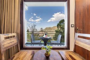 a balcony with a table and chairs and a large window at Kasauli Hills Hotel in Kasauli