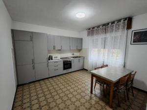 a kitchen with white cabinets and a table and chairs at Appartamento Pini Nicolina s2 in Tirano