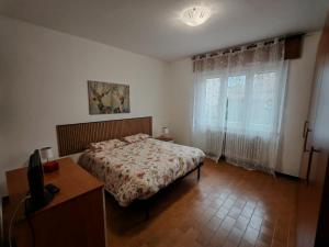 a bedroom with a bed and a desk and a window at Appartamento Pini Nicolina s2 in Tirano
