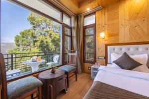 a bedroom with a bed and a balcony with a view at Kasauli Hills Hotel in Kasauli