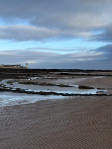 a sandy beach with a lighthouse in the distance at Paws A While in Mainsriddle