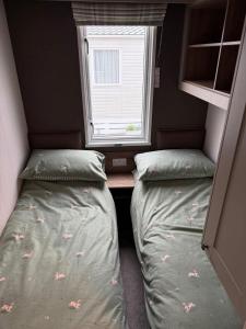 a small room with two beds and a window at Paws A While in Mainsriddle