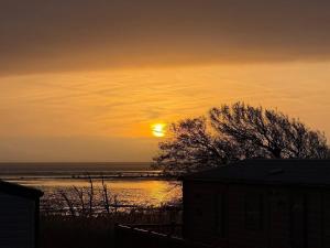 a sunset over a body of water with the sun at Paws A While in Mainsriddle