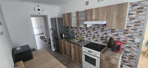 a kitchen with wooden cabinets and a black refrigerator at Appartement GGCH 4 chambres in Montélimar